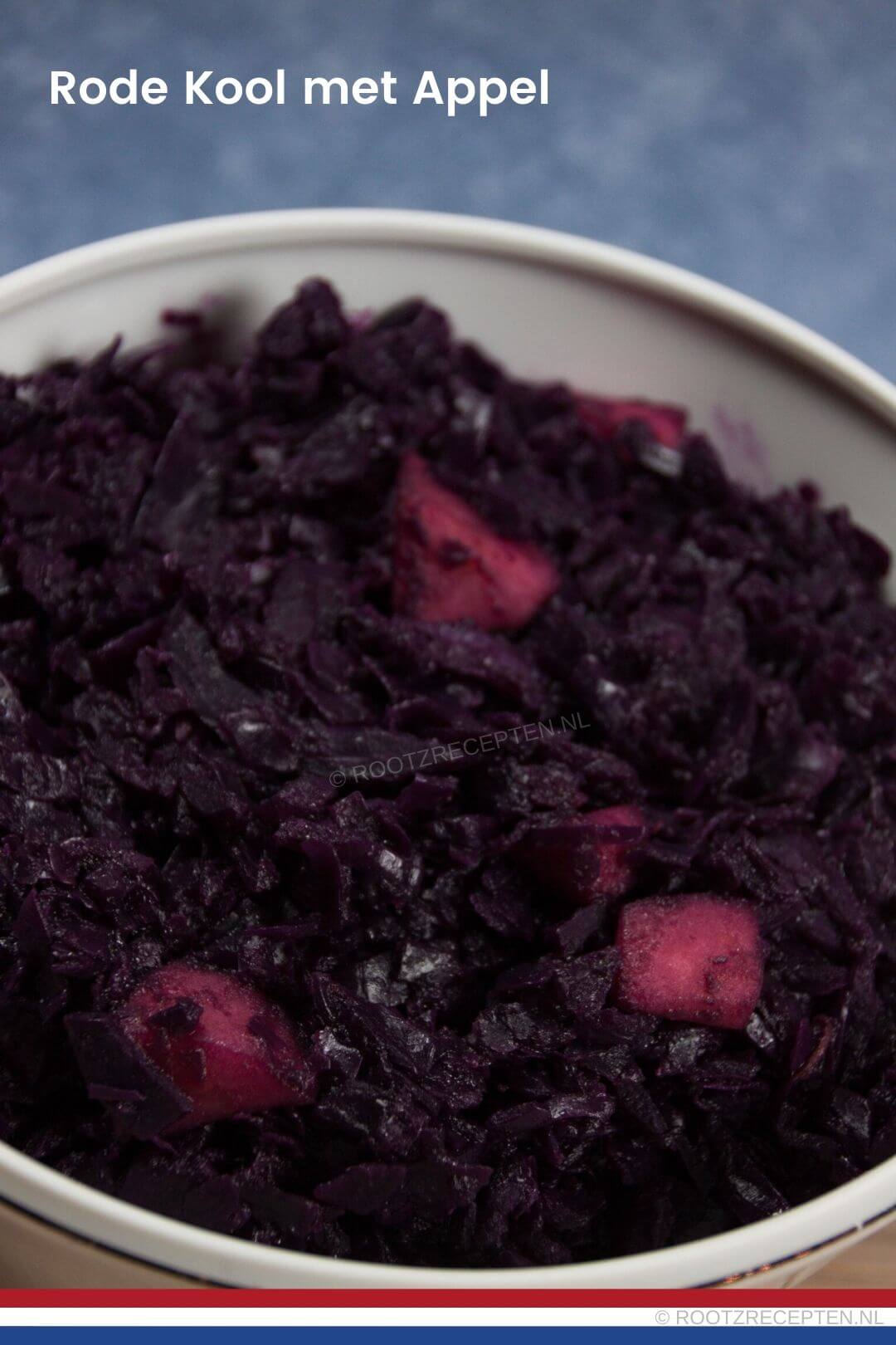 close-up van rode kool met appels in een witte schaal met een blauwe achtergrond